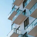 Stylish residential building featuring glass balconies against a clear blue sky.